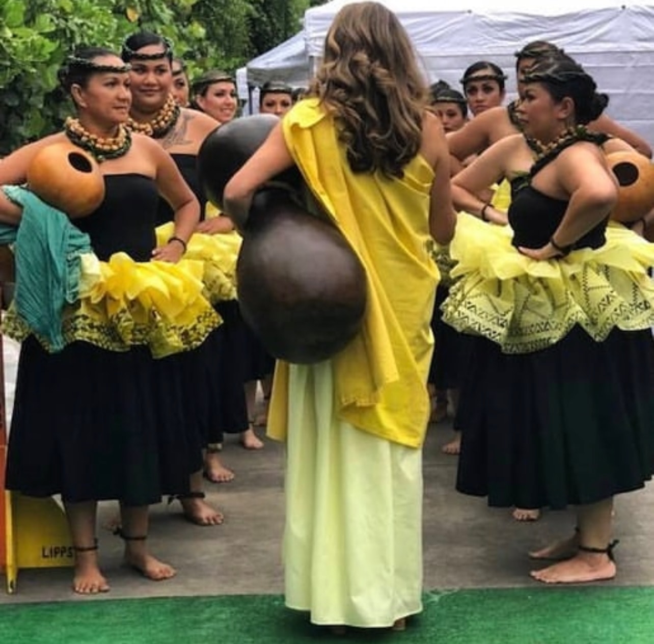Kumu Kahelelani Alohikea-Smith with students of Hālau Kaʻeaikahelelani ready for a performance in Kailua-Kona, holding ipu heke gourds in traditional attire